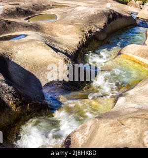 Blick aus der Nähe auf einen gewundenen Gebirgsbach, der über einen glatten Felsvorsprung in den Drakensberg-Bergen fließt Stockfoto