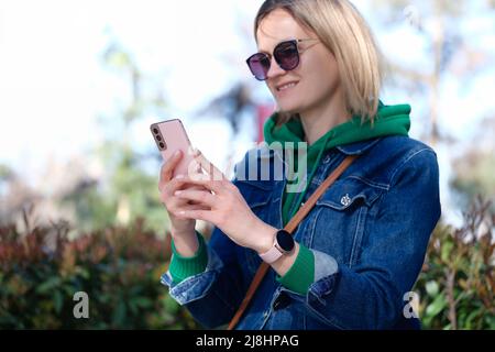 Frau, die auf den Smartphone-Bildschirm blickt und lächelt Stockfoto