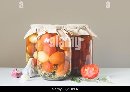 Hausgemachte fermentierte Tomaten in Gläsern auf beigem Hintergrund. Konzept Gemüsekonserven. Stockfoto