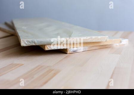 Möbelbrett in Zellophan-Verpackung auf Holzhintergrund. Holzdiele. Stockfoto