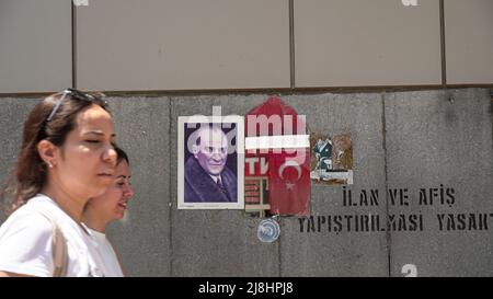 Izmir, Türkei. 15/05/2022, Casual Menschen sind zu Fuß und vorbei vor einem Spiegel mit Spiegelung einer türkischen Flagge und Atatürks Plakat an der Wand auf der Straße im täglichen Leben von Izmir, Türkei. Stockfoto