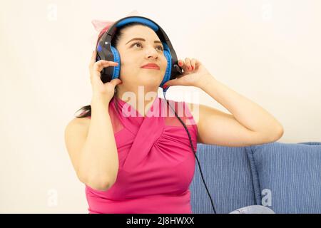 Junge schöne Studentin, die Musik mit blauen Kopfhörern hört Stockfoto