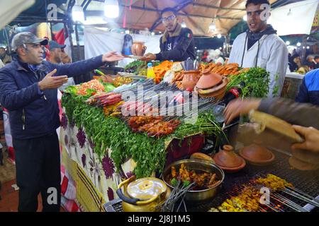 MARRAKESCH, MAROKKO - 20. FEBRUAR 2022: Lebensmittelhändler auf dem Jemaa el-Fnaa-Markt in Marrakesch. Der Platz ist als UNESCO-Meisterwerk von Intang gelistet Stockfoto