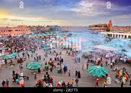 MARRAKESCH, MAROKKO - 20. FEBRUAR 2022: Besucher besuchen den Markt auf dem Platz Jemaa el-Fnaa in Marrakesch, Marokko. Der Platz ist als UNESCO-Masterpiec gelistet Stockfoto