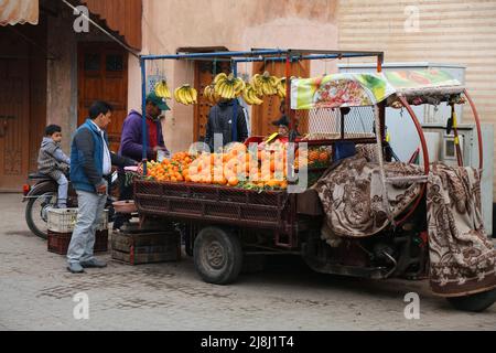 MARRAKESCH, MAROKKO - 20. FEBRUAR 2022: Die Menschen besuchen Obstverkäufer-Warenkorb in Medina (Altstadt) der Stadt Marrakesch, Marokko. Das historische Medina Viertel ist Stockfoto