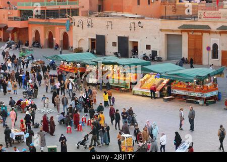 MARRAKESCH, MAROKKO - 20. FEBRUAR 2022: Menschen besuchen den Jamaa el-Fnaa-Markt der Stadt Marrakesch, Marokko. Der Platz ist als UNESCO-Masterpiec gelistet Stockfoto