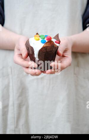 Frau hält glasierte Osterkuchen mit Schokolade und Süßigkeiten, Hausküche Hintergrund dekoriert Stockfoto