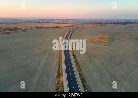 Luftaufnahme einer leeren Intercity-Straße mit asphaltierter Oberfläche und weißen Markierungen am Abend Stockfoto