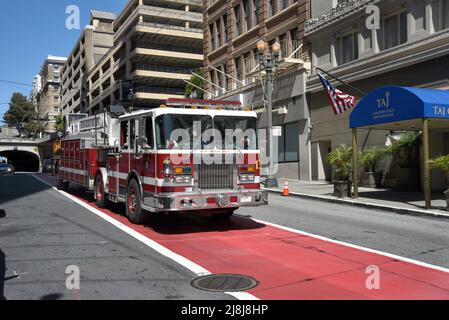 Ein Deichselfeuerwagen mit Lenkrädern vorne und hinten fährt in San Francisco, Kalifornien, entlang einer Straße. Im Heck sitzt ein Bodenbearbeitungsmann. Stockfoto
