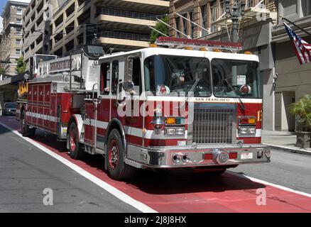 Ein Deichselfeuerwagen mit Lenkrädern vorne und hinten fährt in San Francisco, Kalifornien, entlang einer Straße. Im Heck sitzt ein Bodenbearbeitungsmann. Stockfoto