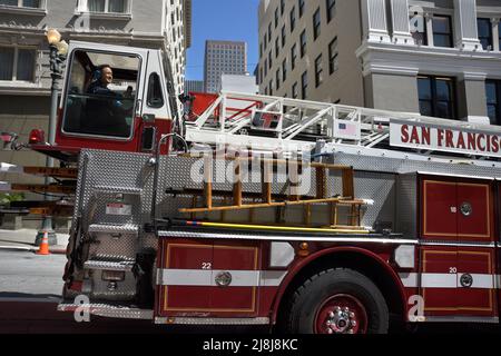 Ein Deichselfeuerwagen mit Lenkrädern vorne und hinten fährt in San Francisco, Kalifornien, entlang einer Straße. Im Heck sitzt ein Bodenbearbeitungsmann. Stockfoto