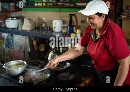 Frau lächelt, als sie in Costa Rica traditionelles Frühstück kocht. Stockfoto