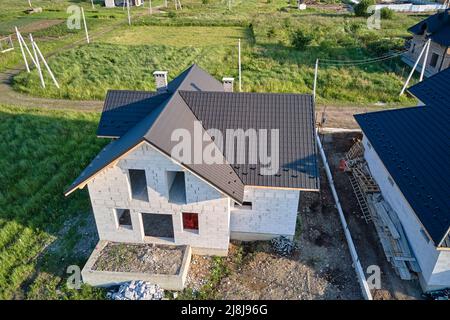 Luftaufnahme des unfertigen Hauses mit belüftetem Leichtbetonwänden und Holzdachrahmen, der mit Metallfliesen im Bau bedeckt ist Stockfoto