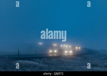 Autos auf einer Kurve durchfahren neblige Fahrkonditonen entlang der Interstate 90 in Montana, USA Stockfoto