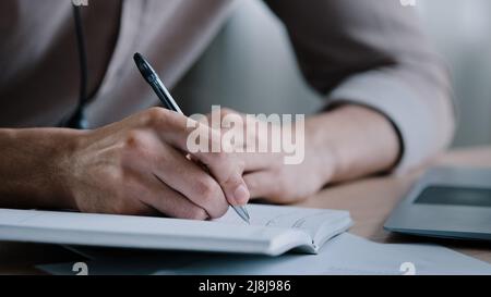 Nahaufnahme unbekannt rechtshändigen männlichen Geschäftsmann schreiben Notizen Geschäftsideen beim Veranstalter Schriftsteller sitzen zu Hause Büro halten Stift Nachricht Informationen Aufgaben in Stockfoto