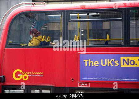 Passagiere, einige tragen eine Maske, andere nicht, werden in einem Doppeldeckerbus in der City of London gesehen. Stockfoto