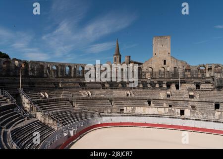 Arles Amphitheater (erbaut 90 n. Chr.). Die Türme auf der Spitze sind mittelalterliche Extras. Im Hintergrund der Glockenturm von Église Couvent des Cordeliers. Arles. Stockfoto