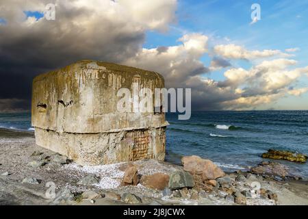 An einem sandigen, wilden, breiten Strand in der Nähe des ruhigen, grünlich ruhigen Schwarzen Meeres steht seit dem Zweiten Weltkrieg ein kleiner verlassene Bunker aus Beton Stockfoto