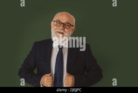 Selbstbewusster männlicher Lehrer oder Professor mittleren Alters, der vor einem leeren Kreidetafel steht. Lustiger Professor oder Wissenschaftler in einem eleganten schwarzen Anzug Stockfoto