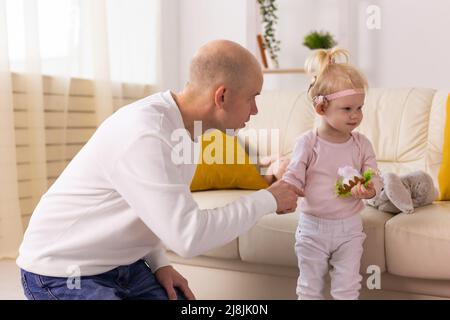 Baby mit Cochlea-Implantaten spielt mit ihrer Mutter und ihrem Vater zu Hause. Stockfoto