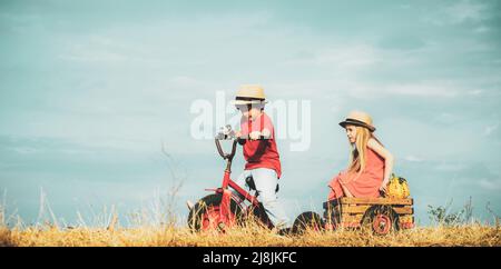 Zwei Kinder haben Spaß im Feld vor blauem Himmel Hintergrund. Glückliche Kinder Bauern arbeiten mit Spud auf dem Frühlingsfeld. Kind und Gemüse auf dem Stockfoto