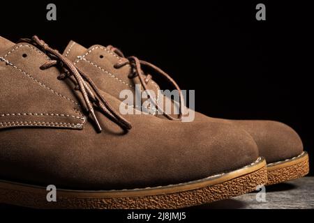 Braune Schuhe mit Schnürsenkeln auf schwarzem Hintergrund. Seitenansicht, Nahaufnahme Stockfoto