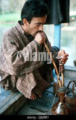 Mann raucht Wasserleitung in Srinagar, Kaschmir 1986 Stockfoto