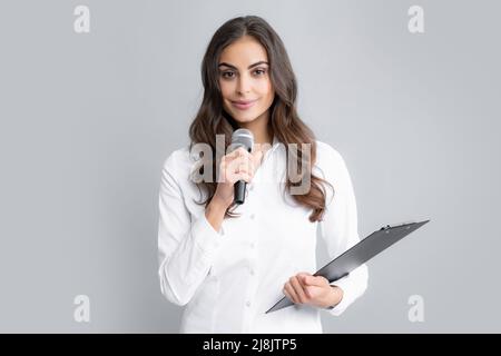 Lächelnde junge Frau als Reporterin mit Mikrofon und Klemmbrett. Journalistin mit Mikrofon und Clipboard. Stockfoto