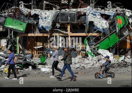 Irpin, Ukraine. 16.. Mai 2022. Die Menschen gehen an einem zerstörten Einkaufszentrum vorbei, das durch den Beschuss der russischen Armee in der Stadt Irpin in der Nähe der ukrainischen Hauptstadt Kiew beschädigt wurde. Russland marschierte am 24. Februar 2022 in die Ukraine ein und löste damit den größten militärischen Angriff in Europa seit dem Zweiten Weltkrieg aus (Foto: Sergei Chuzavkov/SOPA Images/Sipa USA) Quelle: SIPA USA/Alamy Live News Stockfoto