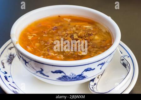Schüssel mit traditioneller chinesischer saurer und würziger Suppe auf einem Teller mit Löffel Stockfoto