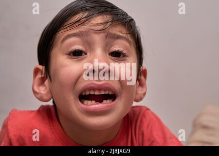 Nahaufnahme eines kleinen brünetten lateinischen Jungen verliert seine ersten Unterzähne Stockfoto