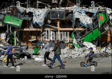 Irpin, Ukraine. 16.. Mai 2022. Die Menschen gehen an einem zerstörten Einkaufszentrum vorbei, das durch den Beschuss der russischen Armee in der Stadt Irpin in der Nähe der ukrainischen Hauptstadt Kiew beschädigt wurde. Russland marschierte am 24. Februar 2022 in die Ukraine ein und löste damit den größten militärischen Angriff in Europa seit dem Zweiten Weltkrieg aus (Bild: © Sergei Chuzavkov/SOPA Images via ZUMA Press Wire) Stockfoto