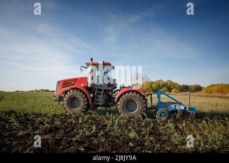 Der Traktor pflügt das Land. Image der Landwirtschaft Stockfoto