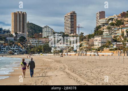 Ein Paar Männer und Frauen, die im Winter am Strand von Levante spazieren gehen, in Benidorm, Provinz Alicante, Bundesland Valencia, Spanien, Europa Stockfoto