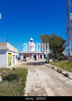 Ein kleiner alter weißer Leuchtturm und ein großer Funkmast an der spanischen Mittelmeerküste zwischen Denia und Xavia Stockfoto
