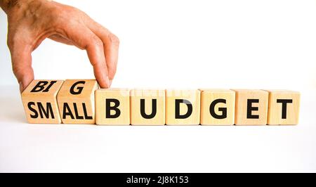 Großes oder kleines Budgetsymbol. Geschäftsmann dreht Holzwürfel und ändert Wörter kleines Budget zu großes Budget. Schöne weiße Tabelle weißen Hintergrund, Kopie Stockfoto