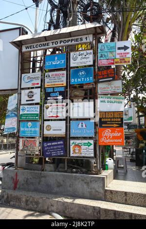 Ein Schild Willkommen bei Poppies 1 mit einer Liste von Hotels und Unternehmen in Poppies Lane in Kuta, Bali, Indonesien. Stockfoto