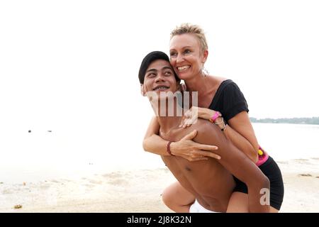 Verliebte Paare, die an einem tropischen Strand reiten Stockfoto