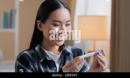 Asiatische Mädchen schwanger glückliches Mädchen überrascht Frau erwartungsvoll Zukunft Mutter weibliche Eltern halten Blick auf positive Schwangerschaft Test erwartet Baby Kleinkind Stockfoto