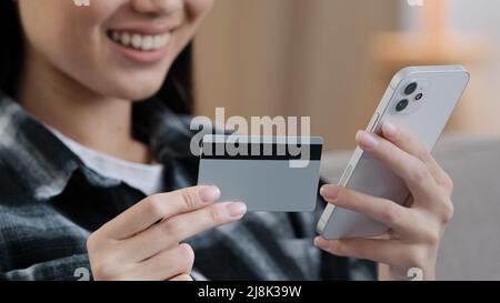 Close-up weibliche Hände unbekannt asiatische Frau hält Bank Kreditkarte Handy macht online Internet-Zahlungen Käufe E-Commerce-Bestellung Stockfoto