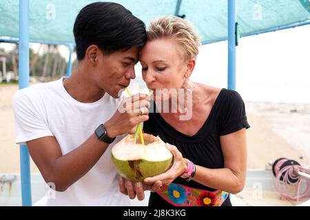 Multikulturelles Paar, das den Saft einer frischen Kokosnuss teilt Stockfoto