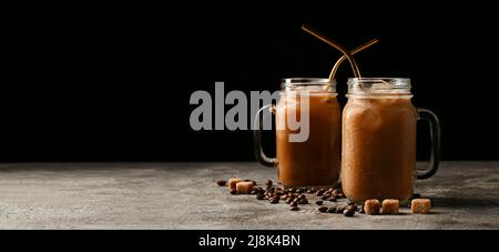 Mason Gläser mit leckeren Eiskaffee mit Milch, Bohnen und Zuckerwürfeln auf dunklem Hintergrund mit Platz für Text Stockfoto