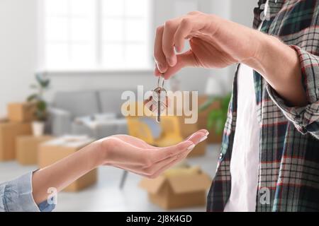 Mann, der der jungen Frau den Schlüssel aus dem Haus gibt. Konzept der Miete oder Kauf neuer Immobilie Stockfoto