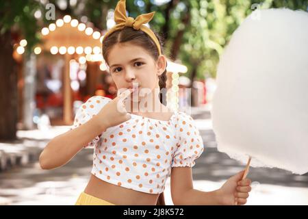 Nettes kleines Mädchen essen Zuckerwatte im Freien Stockfoto