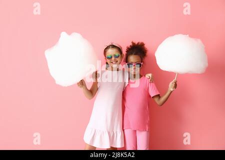 Niedliche kleine Mädchen mit Zuckerwatte auf rosa Hintergrund Stockfoto