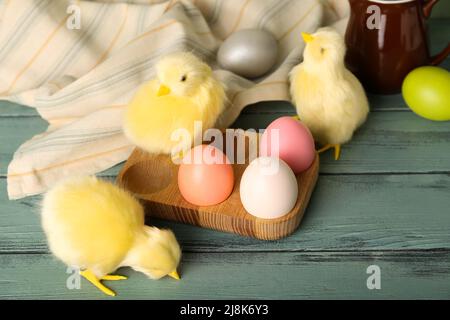 Niedliche Hühner und Ostereier auf Holzhintergrund Stockfoto