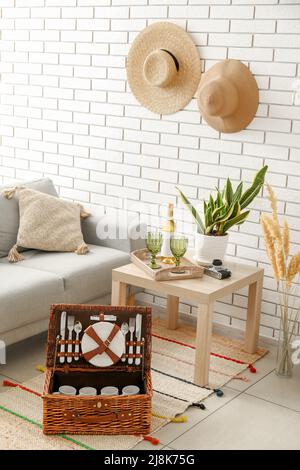 Korbkorb mit Geschirr für Picknick auf Teppich im Wohnzimmer Stockfoto