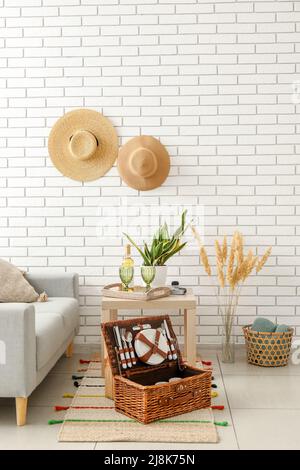 Korbkorb mit Geschirr für Picknick auf Teppich im Wohnzimmer Stockfoto