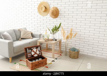 Korbkorb mit Geschirr für Picknick auf Teppich im Wohnzimmer Stockfoto