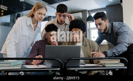 Junge, aufgeregte, glückliche Geschäftsleute, die sich im Büro zusammenfinden, schauen sich den Laptop-Bildschirm an und lesen gute Nachrichten Stockfoto